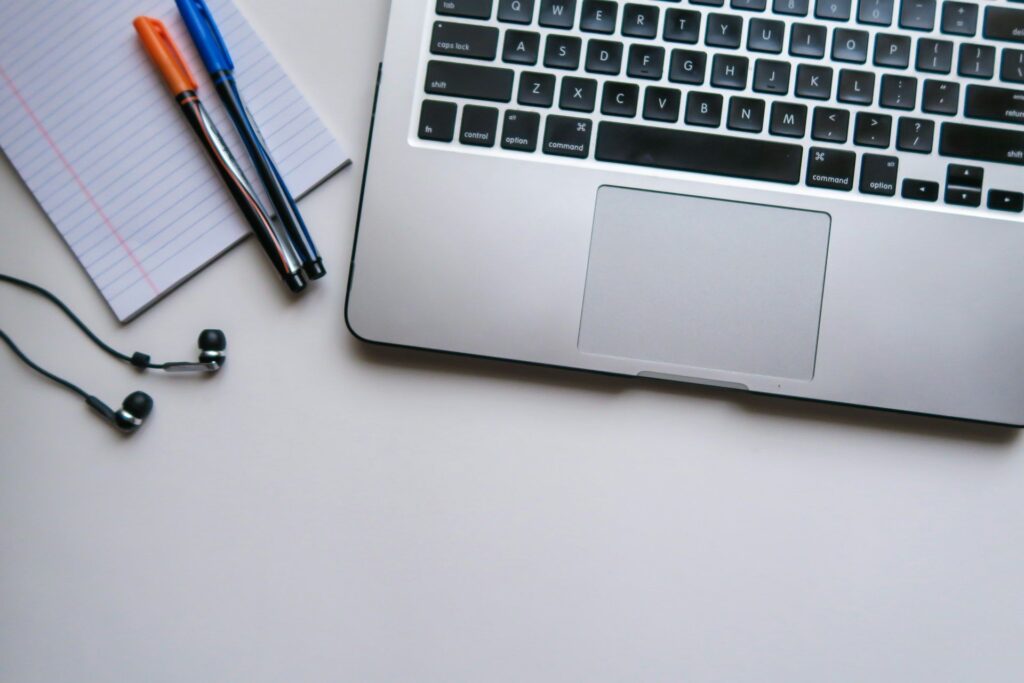 Ordenador portátil y cuaderno de estudios representando la captación de alumnos para academias de oposiciones online